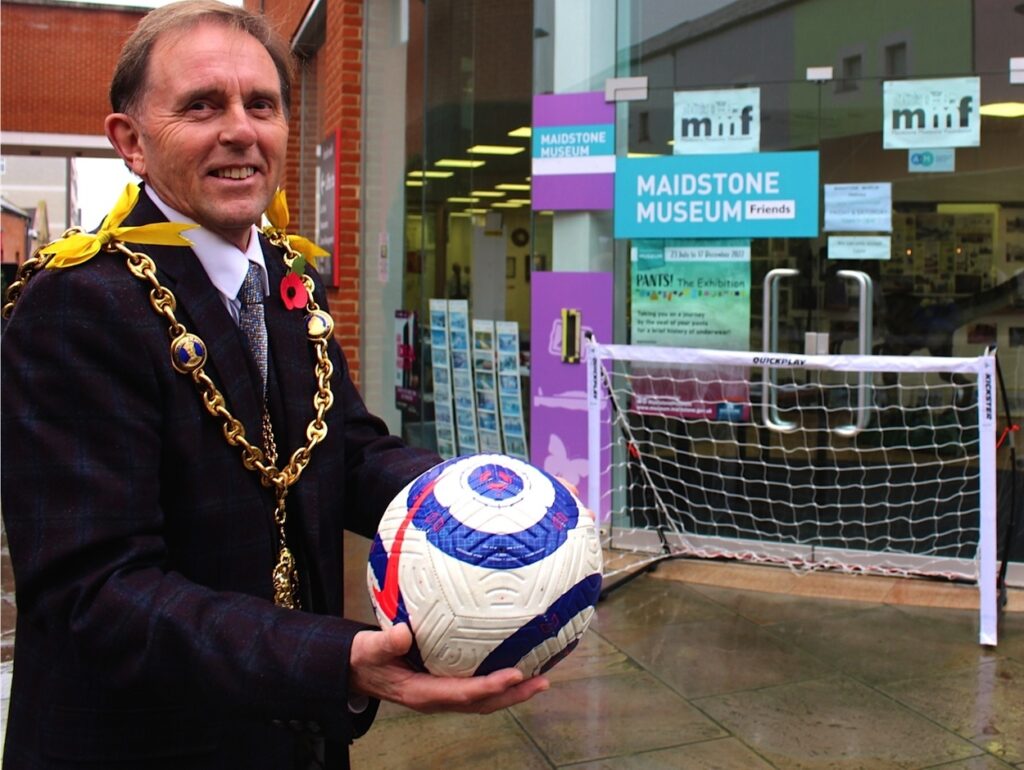 Maidstone Mayor Cllr Derek Mortimer holding Stones' Soccer Show exhibition football at MMFs' shop